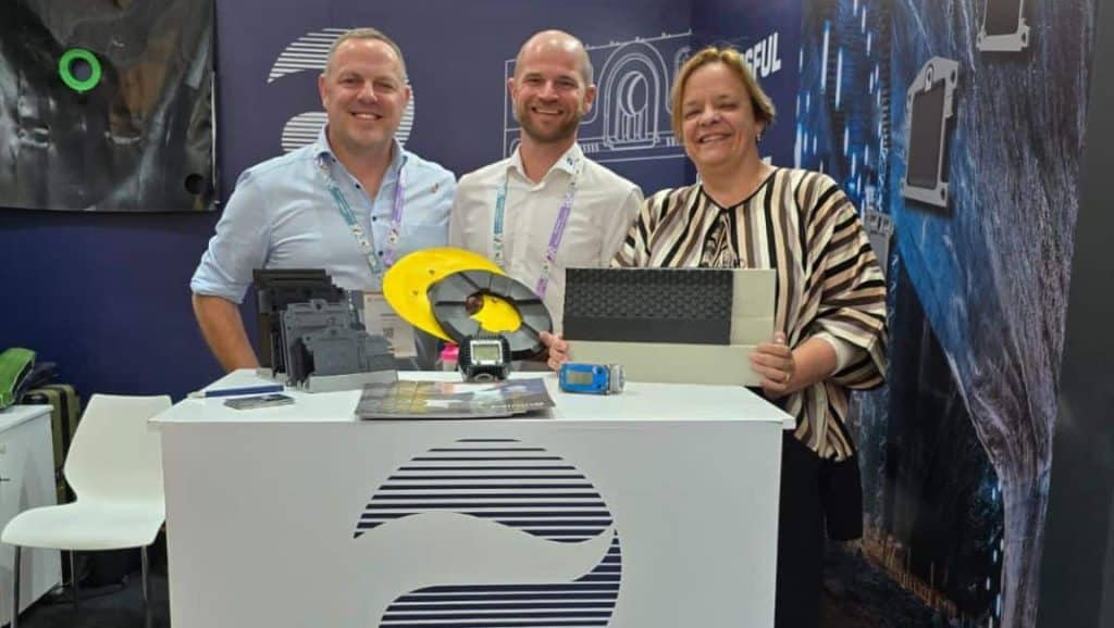 Messestand von JVK Filtration Systems auf einer Fachmesse mit Produktdemonstration am Tresen. Drei Personen im Gespräch über SnapFit-Filterplatten vor gebrandeter Präsentationswand.