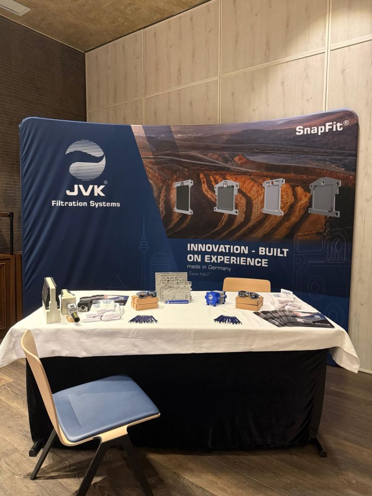Messestand von JVK Filtration Systems mit gebrandeter Rückwand, Produktabbildungen und Slogan „Innovation – Built on Experience“. Auf dem Tisch liegen Muster, Broschüren und Werbematerialien zur Präsentation der Filtrationslösungen.